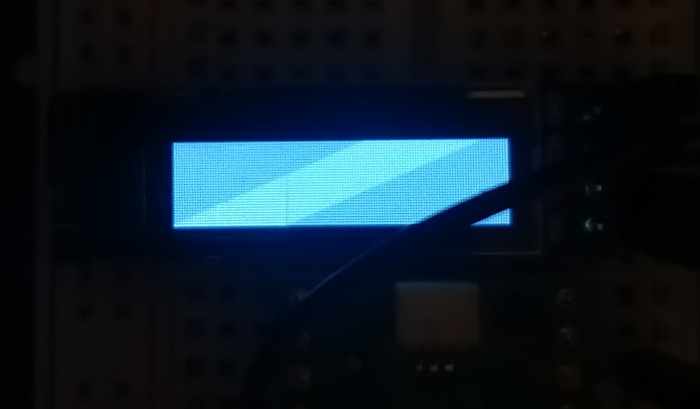 An image of a small OLED display, completely filled with white pixels